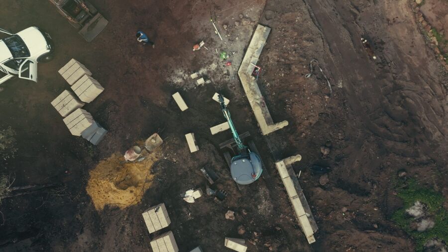 Aerial view of a limestone wall taking shape across a cleared site
