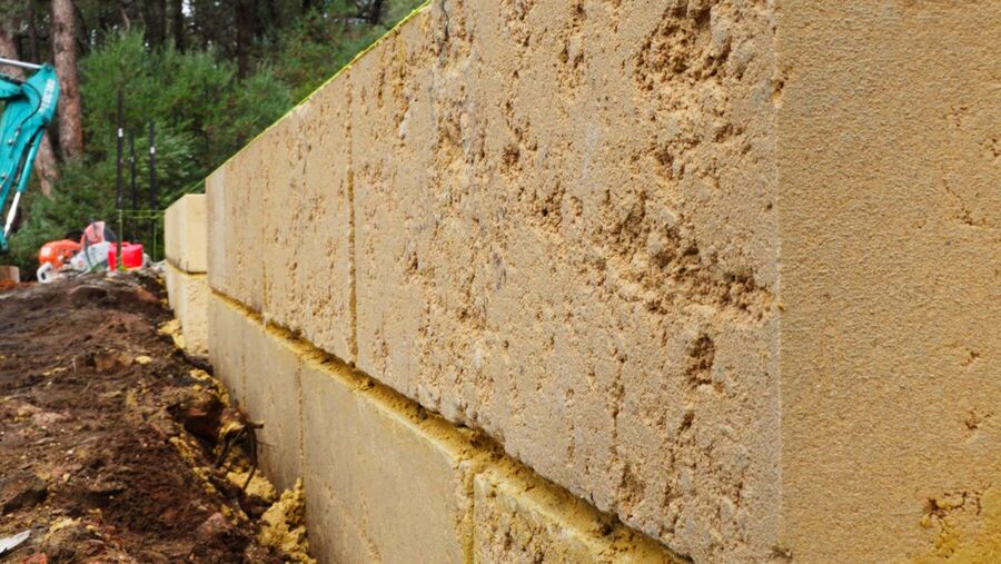 A finished limestone retaining wall with tight, level joints running along a bush block