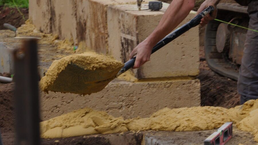 Laying a bed of mortar onto a course of limestone blocks